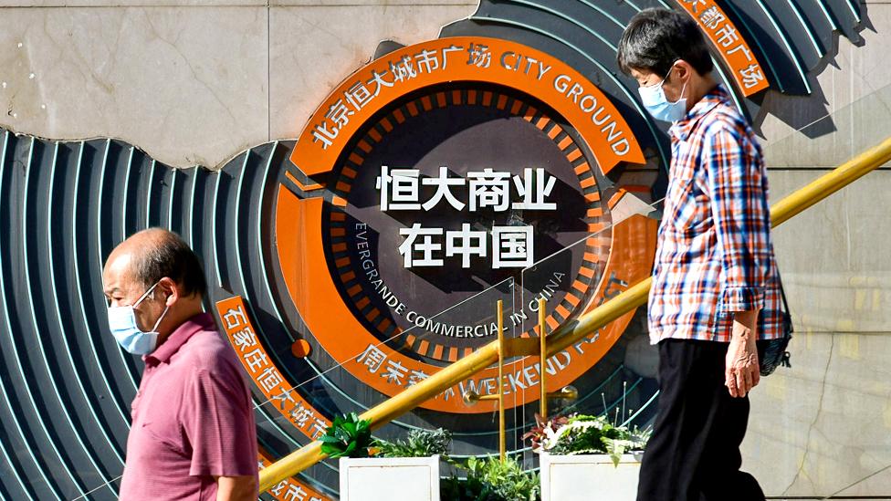 People pass in front of Evergrande group's blueprint for development in China at Evergrande city square, Chaoyang District