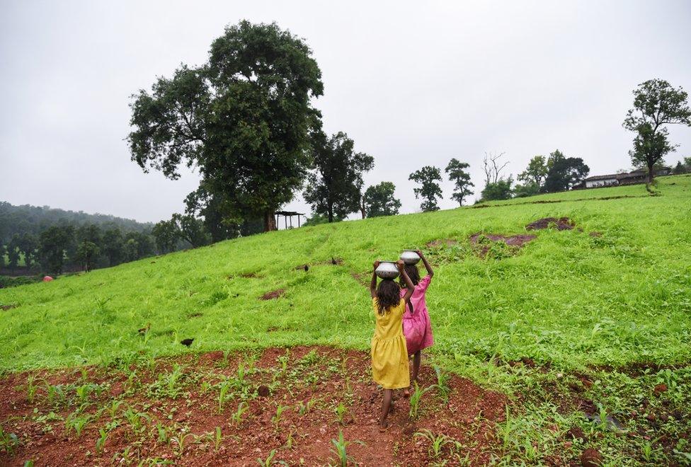 Twin sisters carry water back to their home.