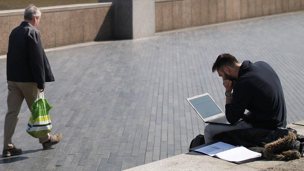 Man working on laptop by the River Thames in London