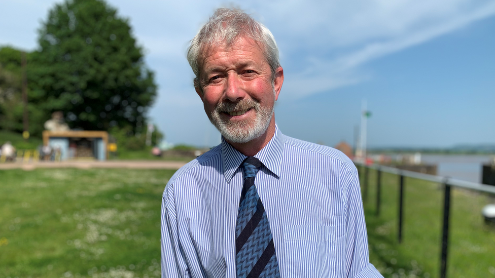 Man in blue shirt and tie stood in front of Lydney Harbour