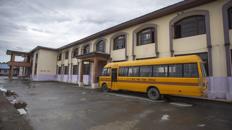 A school bus lies idle next to a school in Kashmir