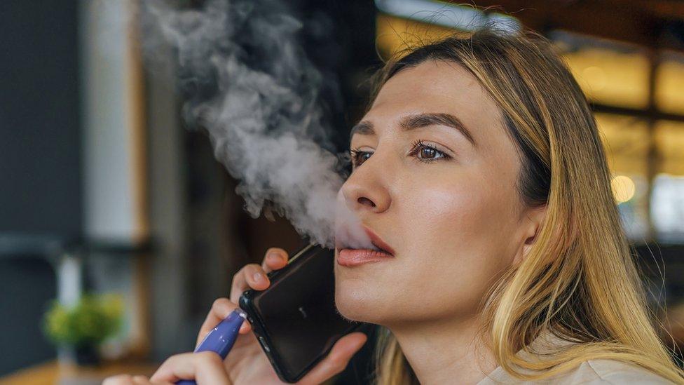 Model posing with a vape