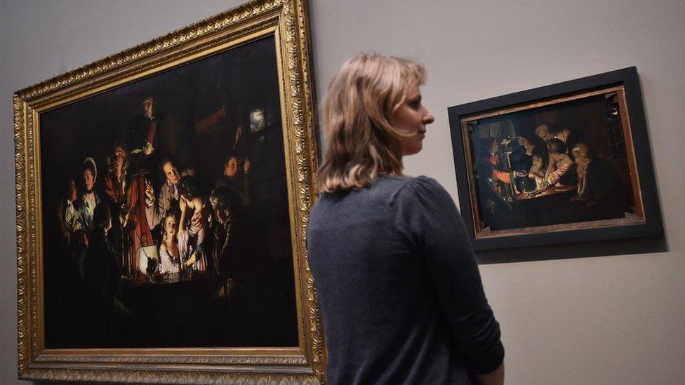 A gallery assistant poses for photographers next to the newly installed sketch of the original painting