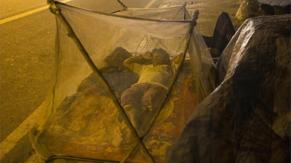 An Indian migrant labourer sleeps near a roadside under mosquitoes nets in New Delhi, India, Wednesday, Sept. 14, 2016