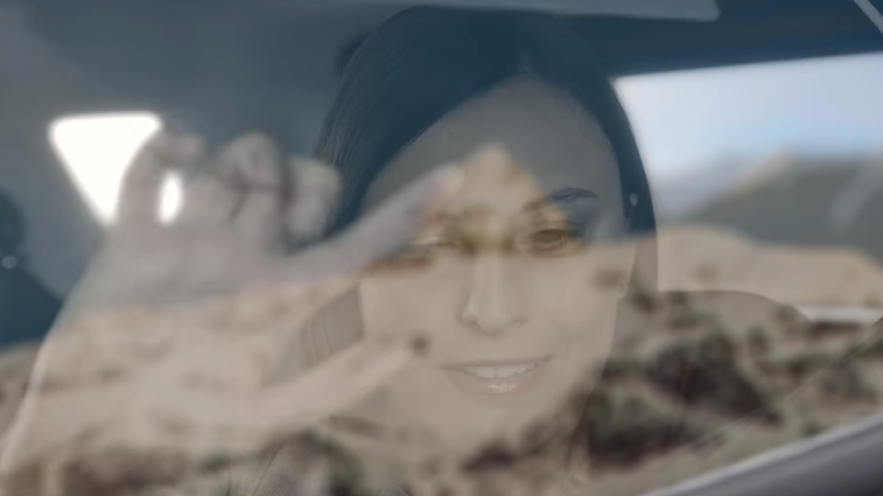 Woman traces landscape on car window