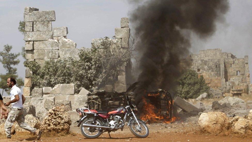 A man runs past a vehicle that rebel fighters say was targeted in a Russian air strike in Hass, in Idlib province, Syria (1 October 2015)