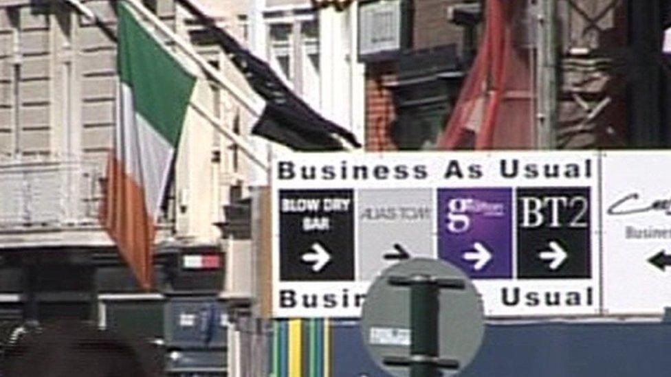 Irish tricolour flies beside 'business as usual' sign in Dublin's main shopping street