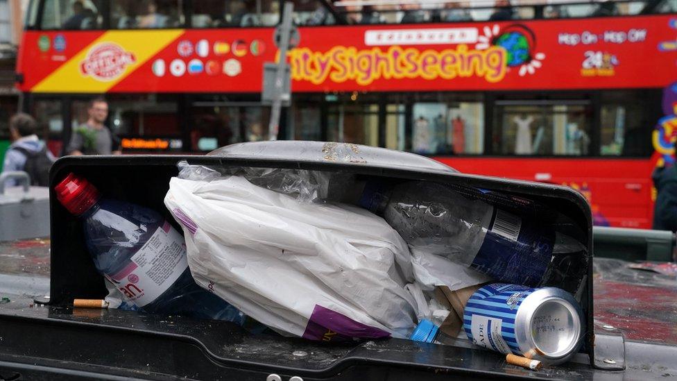 A sightseeing bus passes an overflowing bin in Edinburgh city centre