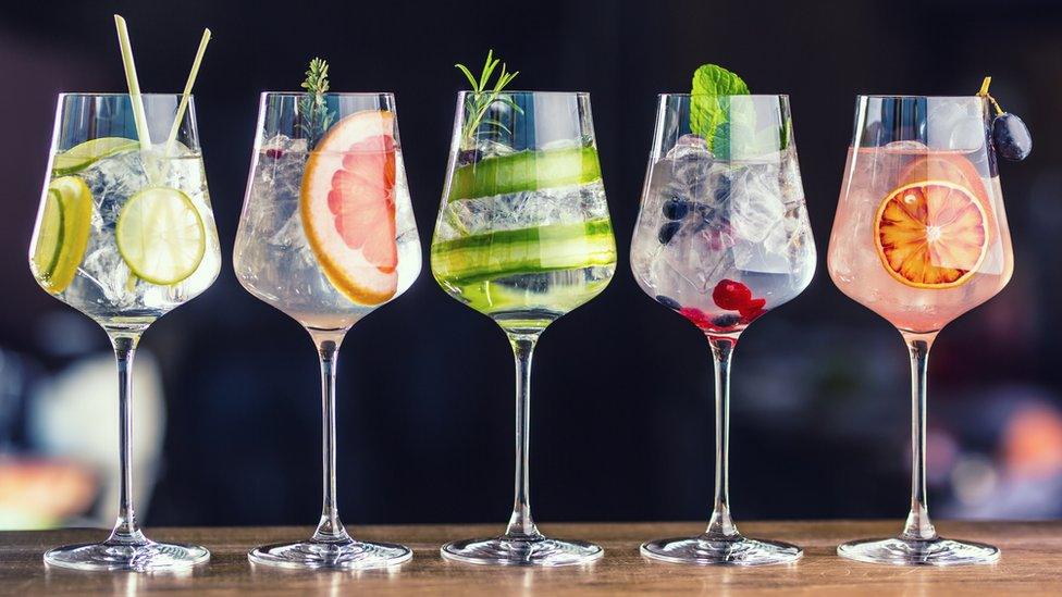 Five colourful gin tonic cocktails in wine glasses