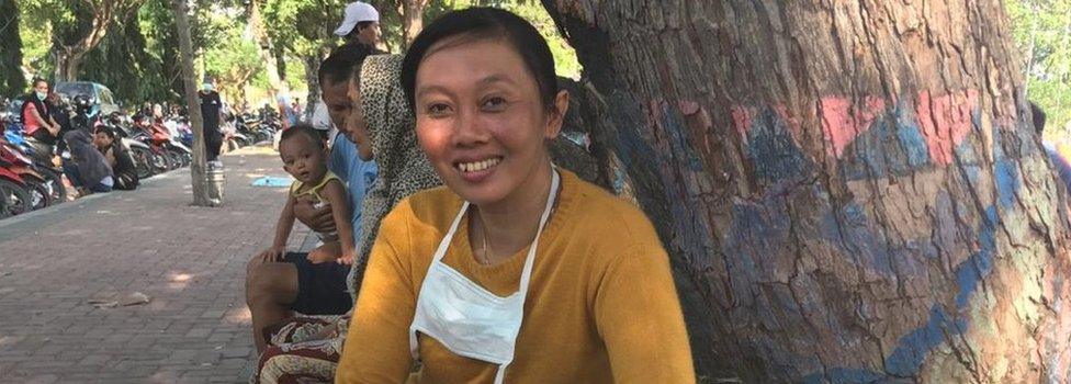 Erna Wahyuni smiles in front of a basket of cabbage