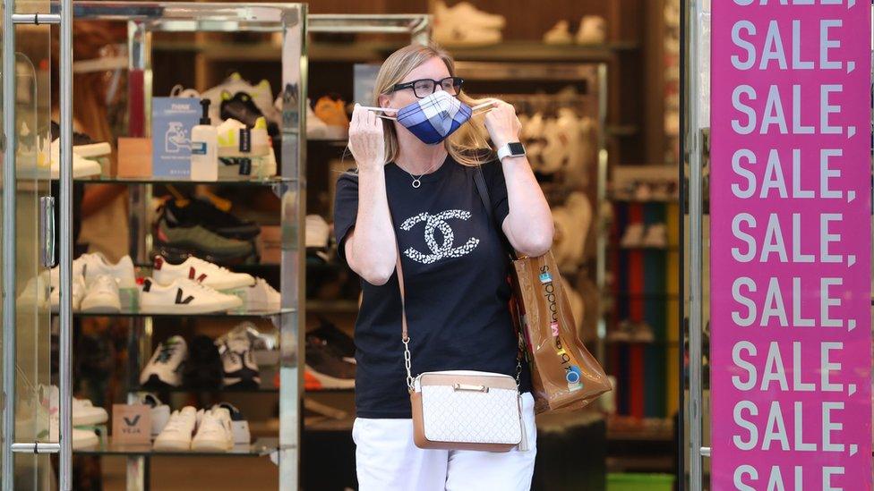 A person removes a face mask (face masks) as they leave a shop in Buchanan Street in Glasgow