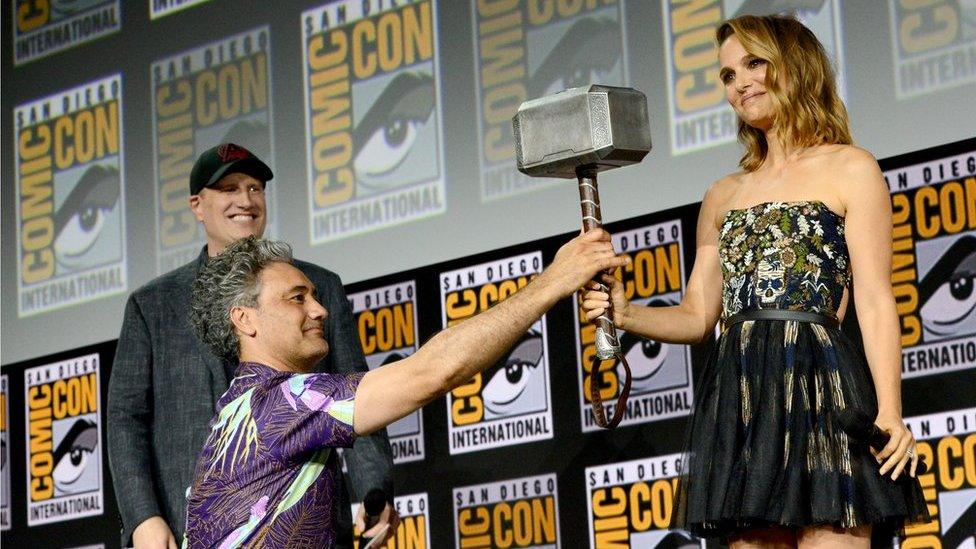 Natalie Portman holding a hammer which has just been handed to her.