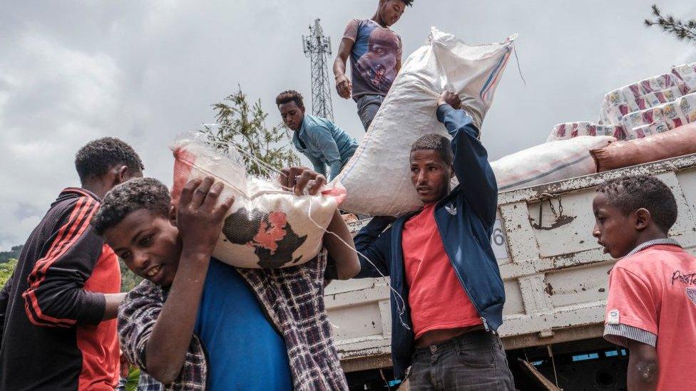 Civilians displaced by fighting in northern Ethiopia off load food and supplies from a truck, provided by the local population, at the Addis Fana School where they are temporary sheltered, in the city of Dessie, Ethiopia, on August 23, 2021