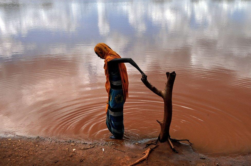 Villagers fetch water from a polluted water hole in the village of Damba in northern Kenya, 2006