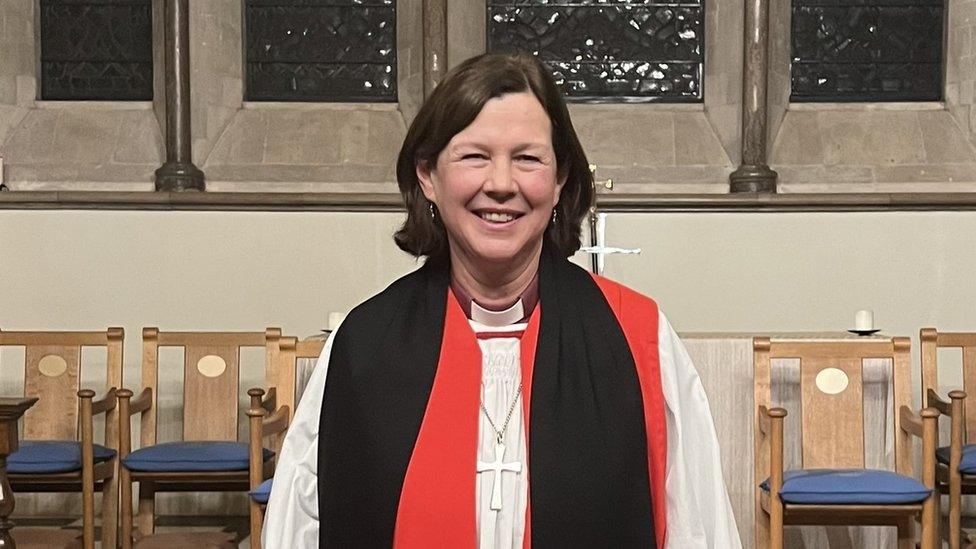 Woman with dark hair in priest's robes