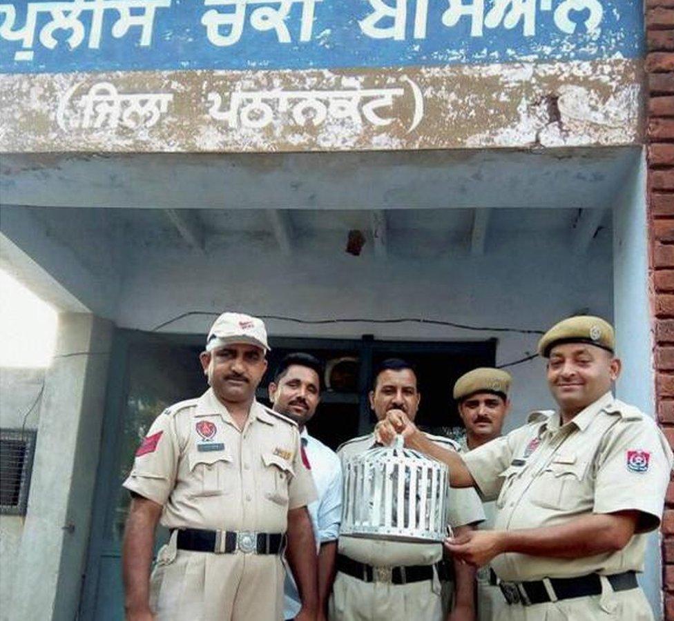 Policemen hold up the spy pigeon