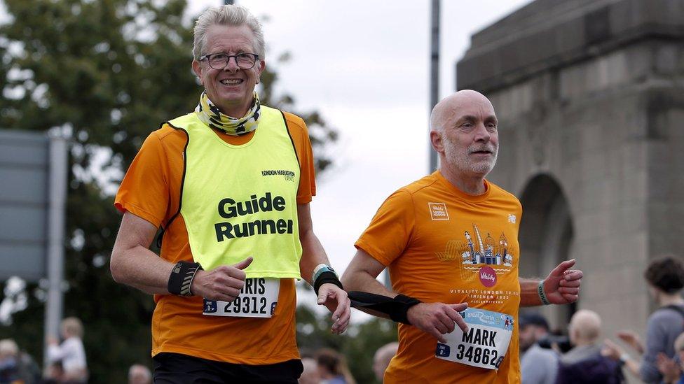 A guide runner and a man run side by side