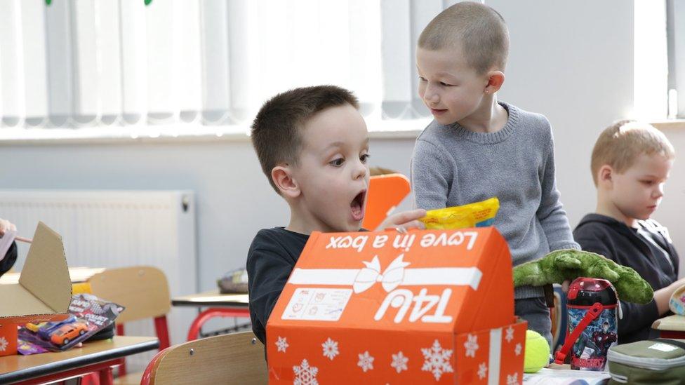 Three children looking at items from one of the gift boxes.