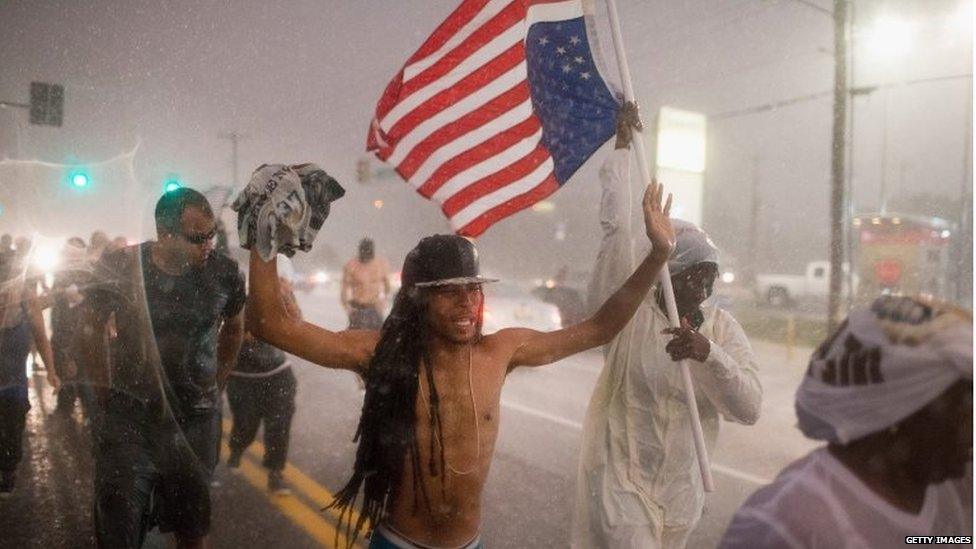 Demonstrators, marking the one-year anniversary of the shooting of Michael Brown, march along West Florrisant Street in a driving rain in Ferguson, Missouri (9 August 2015)