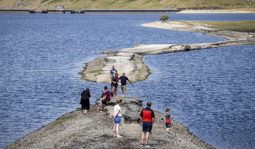 Walkers use a pathway exposed by the falling water level at Spelga Reservoir, in County Down, as Northern Ireland is hit by a water shortage