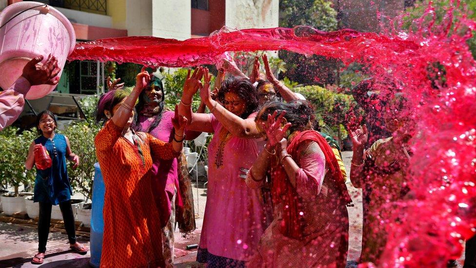 A bucket of red coloured water is thrown over a group of people