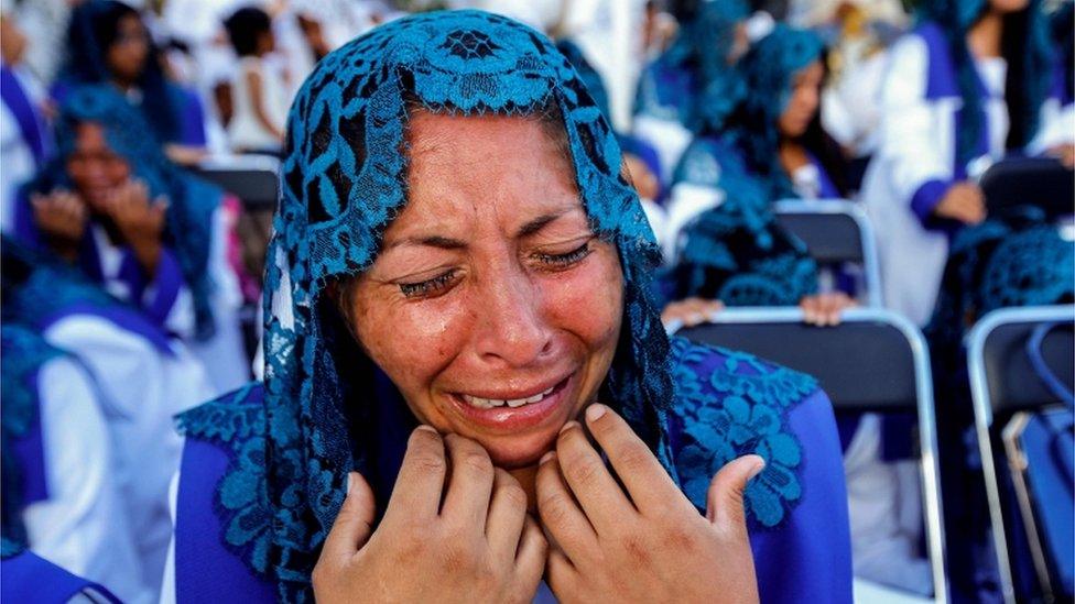 A woman with a blue mantilla cries with emotion during the annual gathering of the Light of the World church