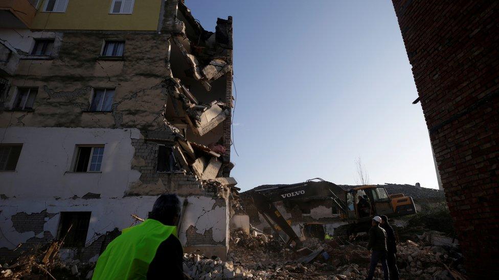 Emergency workers stand in front of rubble