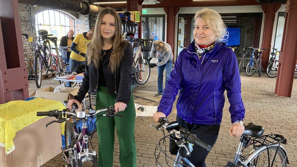 Anastasiia and Kateryna holding their bikes in the bike shop