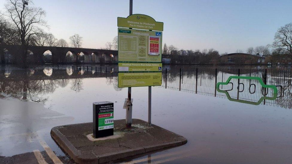 The car park sign and floodwater all around it