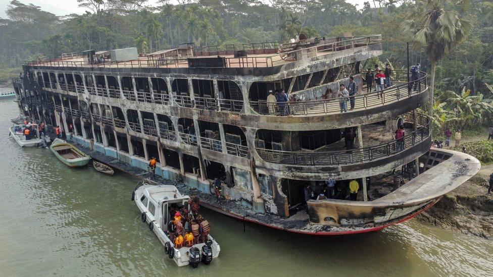 Firefighters and coast guard personnel at the scene of a passenger ferry that caught fire near the southern rural town of Jhalakathi, south of Dhaka in Bangladesh, 24 December 2021