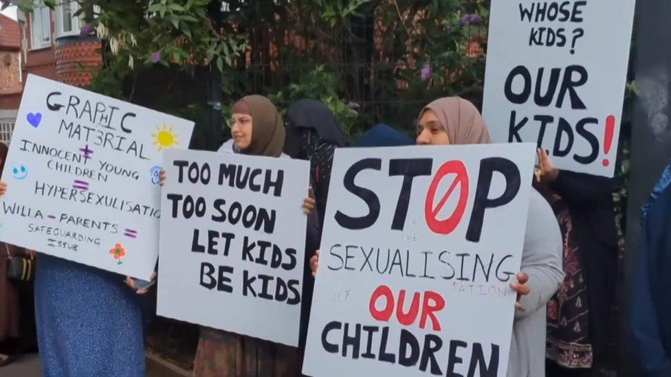 Protestors hold placards saying "stop sexualising our children" and "too much too soon, let kids be kids"