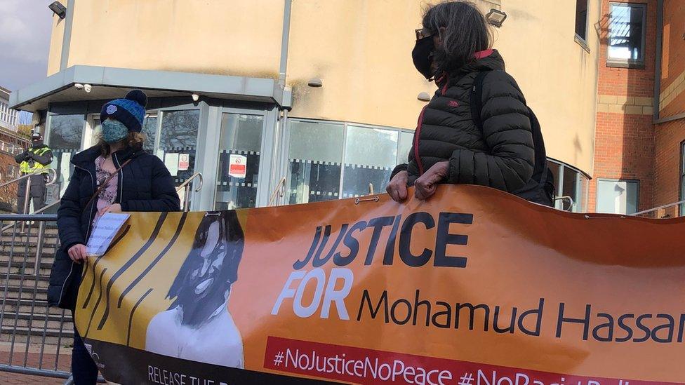 Two supporters carrying a banner are seen outside Cardiff Bay Police Station