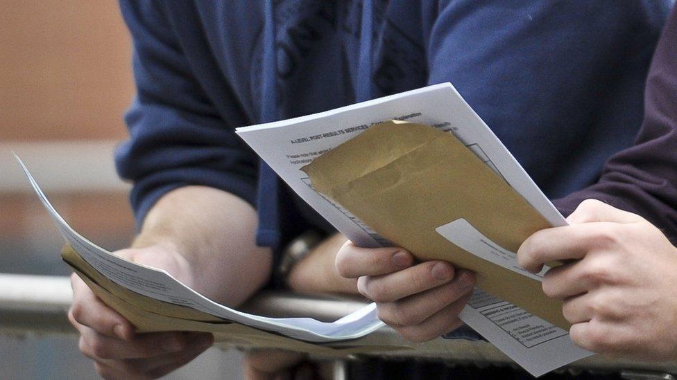 Close up students holding results envelopes