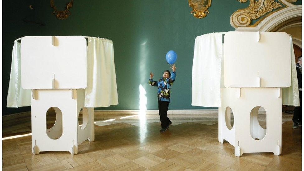 A child plays with a balloon near voting booths in Moscow