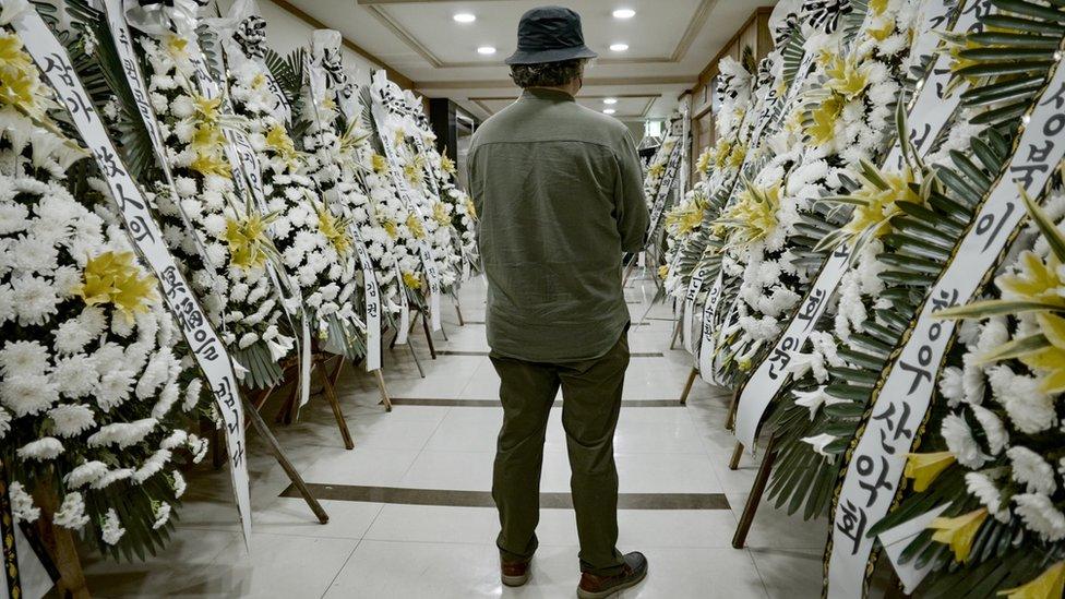 The victim's uncle looks at flowers sent to the funeral home where his niece's body lies