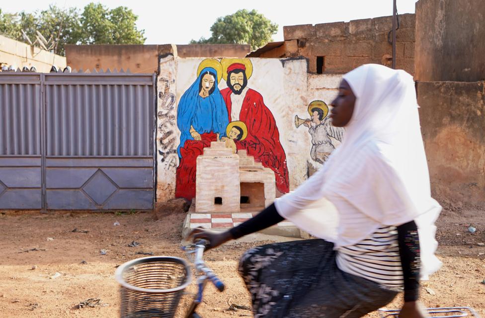 Woman cycling past a mural