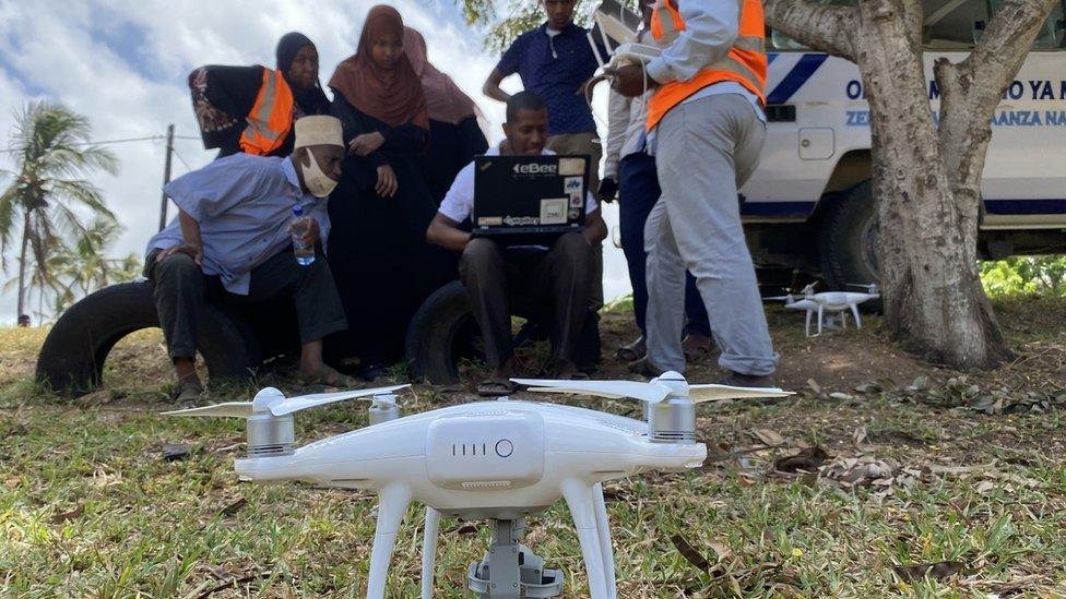 People in Zanzibar looking at a laptop with a drone in the foreground