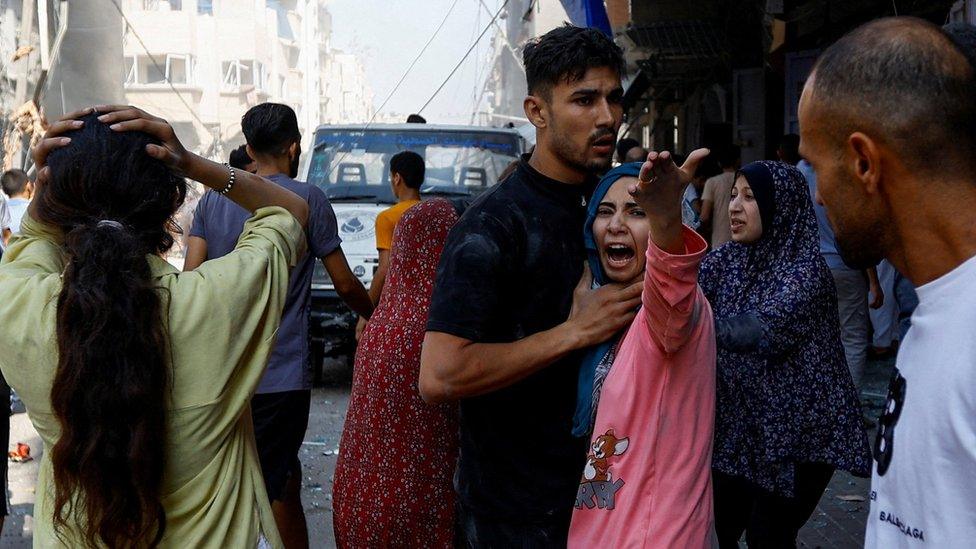 Palestinians react at the scene of an Israeli strike in Khan Younis, in the southern Gaza Strip (24 October 2023)