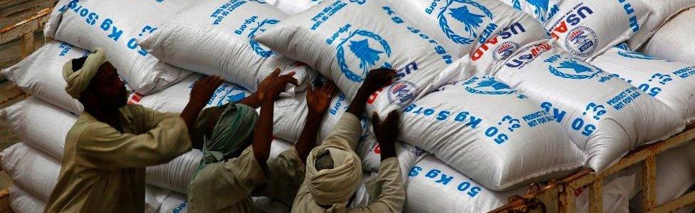 Sudanese workers offload US aid destined for South Sudan from the World Food Programme (WFP) at Port Sudan on March 19, 2017