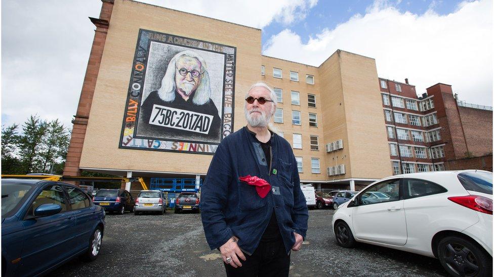 Billy Connolly next to one of his murals