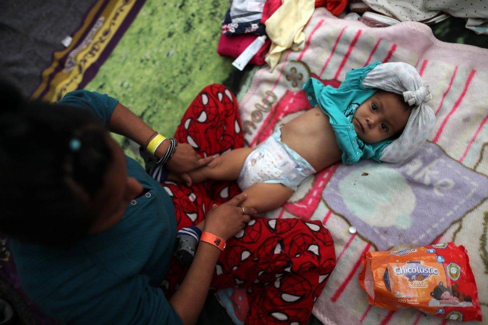 Yeni, 20, from Guatemala, changes the nappy of her one-year-old daughter Marta in a temporary shelter in Tijuana, Mexico, 23 November