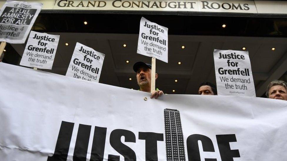 Demonstrators hold placards outside the venue of the inquiry into the Grenfell Tower fire