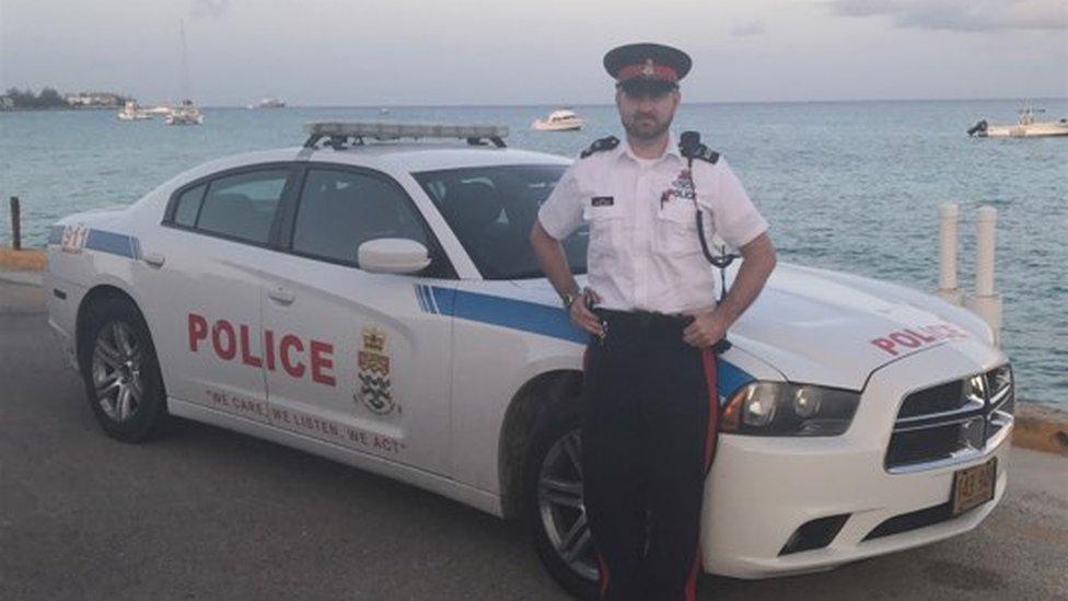 Matthew Thomas by a Cayman Island police car