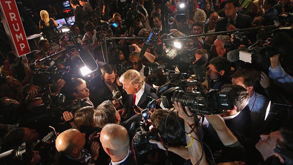 Republican presidential candidate Donald Trump (C) talks to reporters