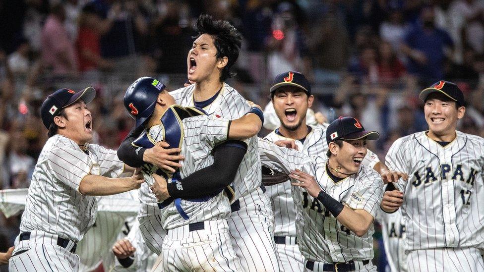 Japanese captain Shohei Ohtani (centre) is embraced by his teammates in celebration after winning the game