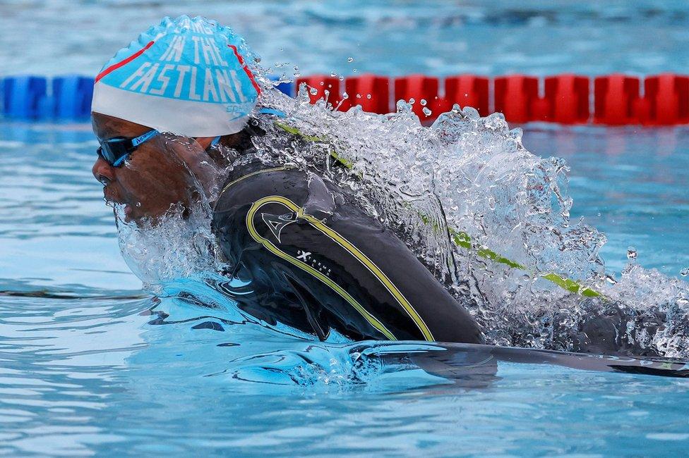 A swimmer breaks the surface of the water as the swim