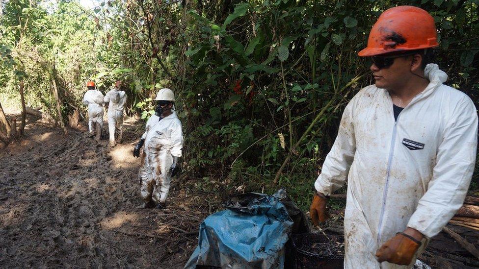 Workers in protective suits help clean up the oil spill