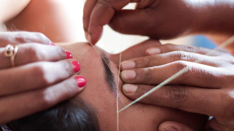 Beautician threading woman's eyebrows - stock photo