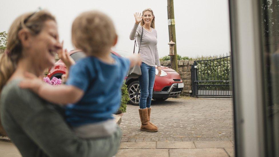 stock image - A women waves goodbye to her mother and son from across the street as she leaves the house.