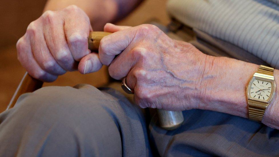 elderly person holding walking stick